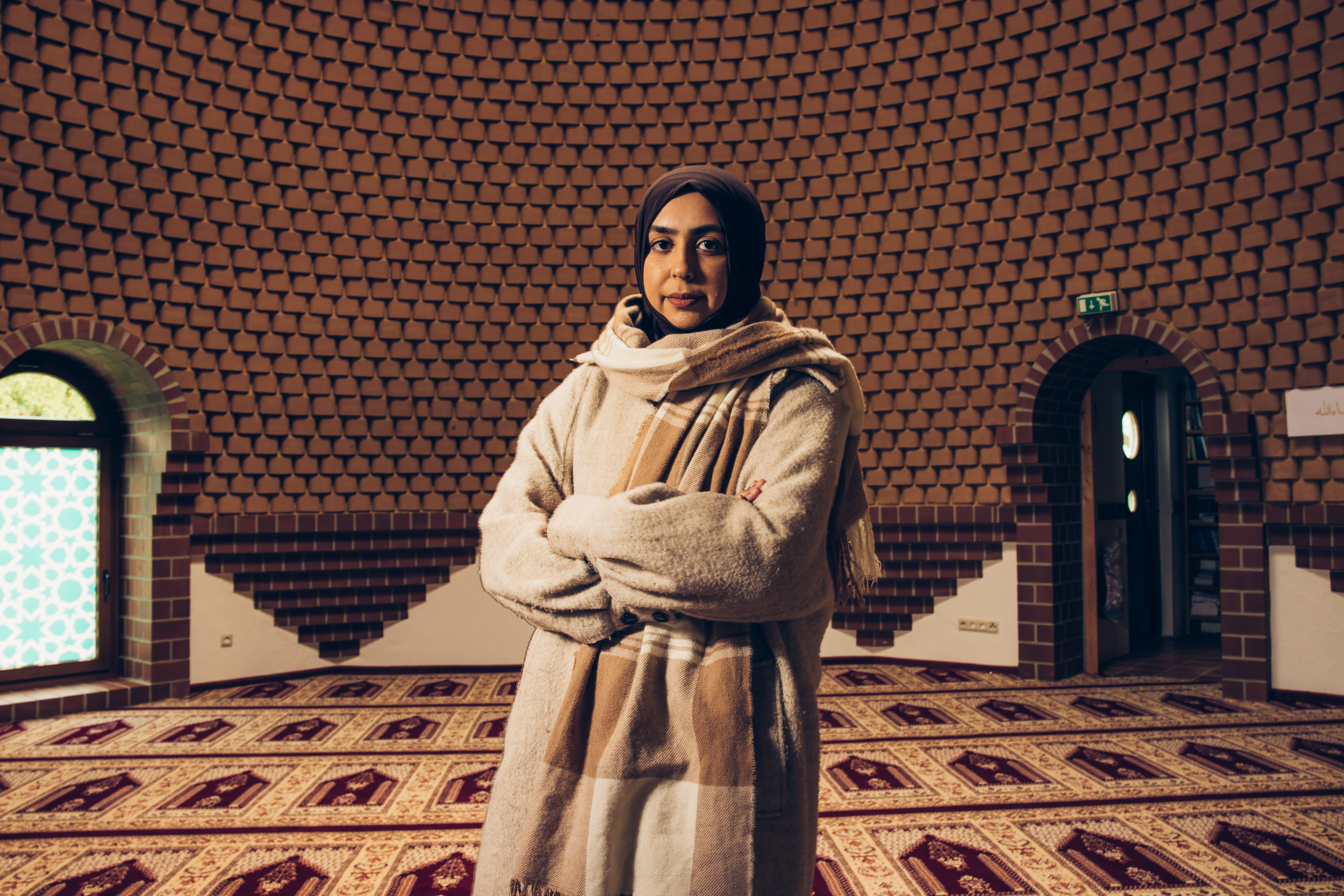 Rameza steht mit verschränkten Armen in der Bait-ul-Muqiet Moschee und blickt in die Kamera. 