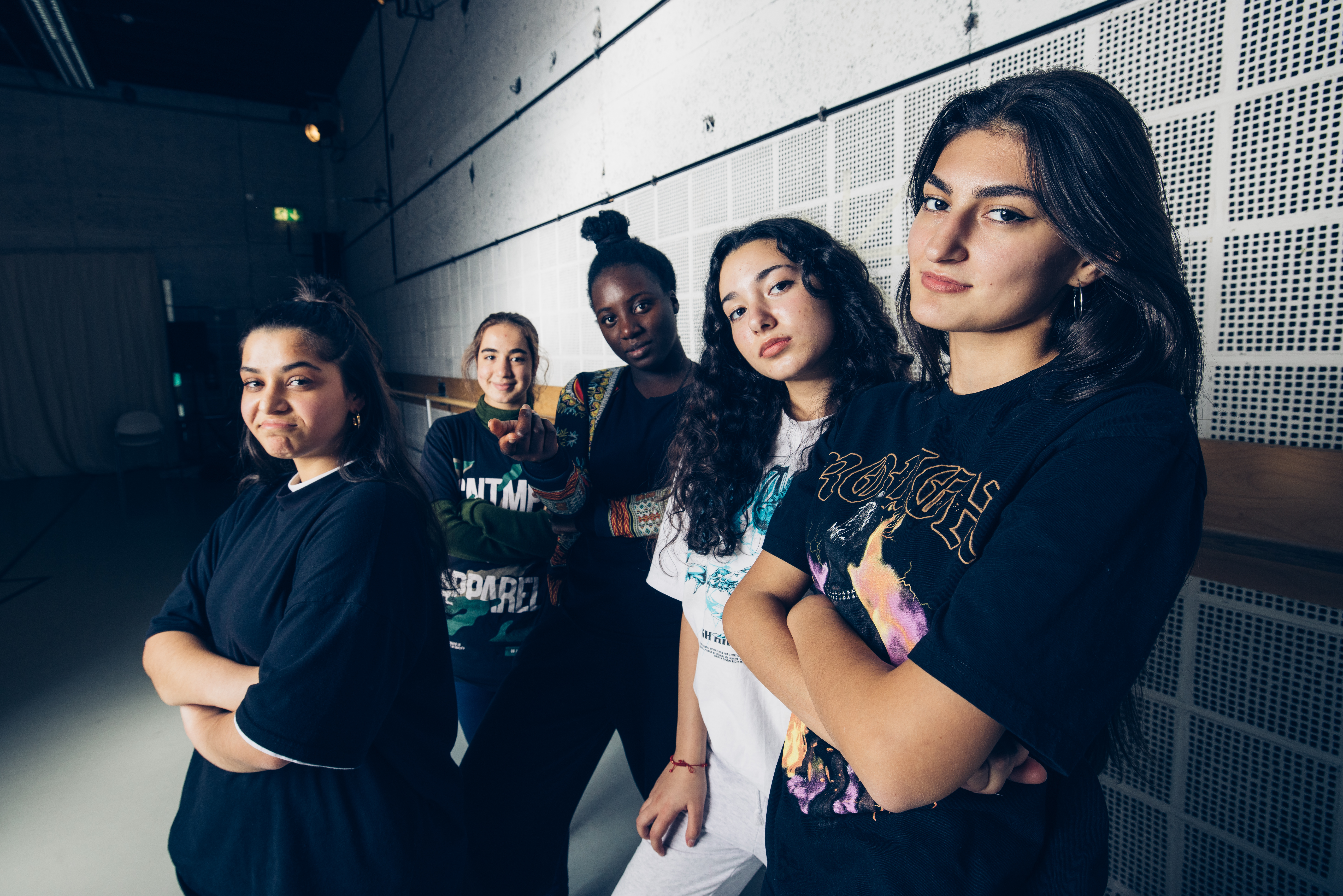 Jenny und vier weitere Personen werden von einem Scheinwerfer beleuchtet und blicken in die Kamera.